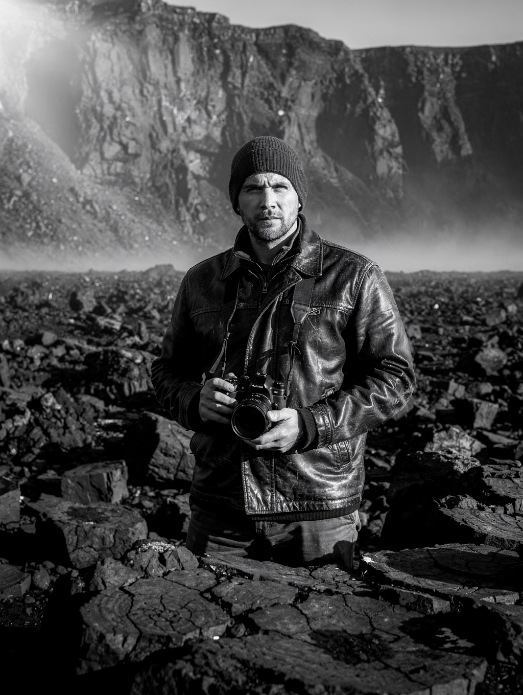 Landscape photographer with field camera amidst volcanic basalt formations